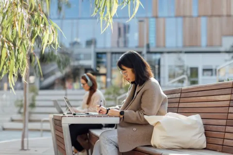 A student studying on their laptop in a student precinct or park.
