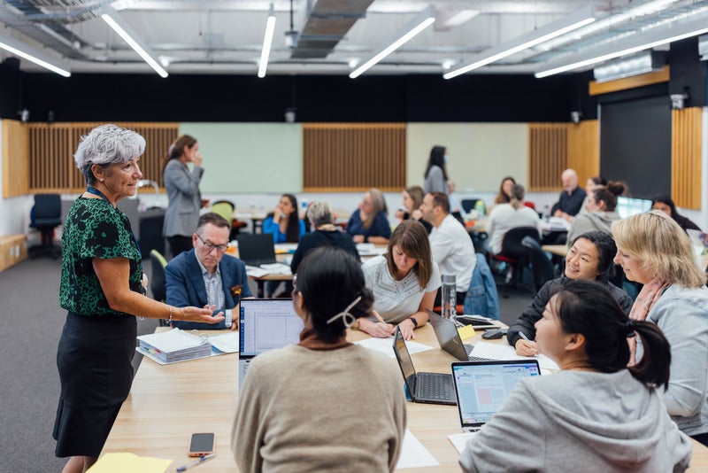 A woman stands before a group, confidently presenting her information to the audience.