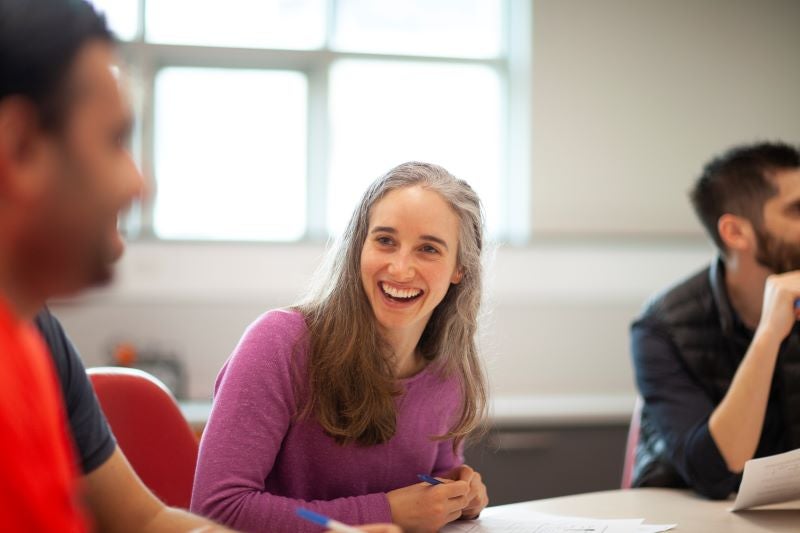 A smiling student in class during a lecture with their course mates.